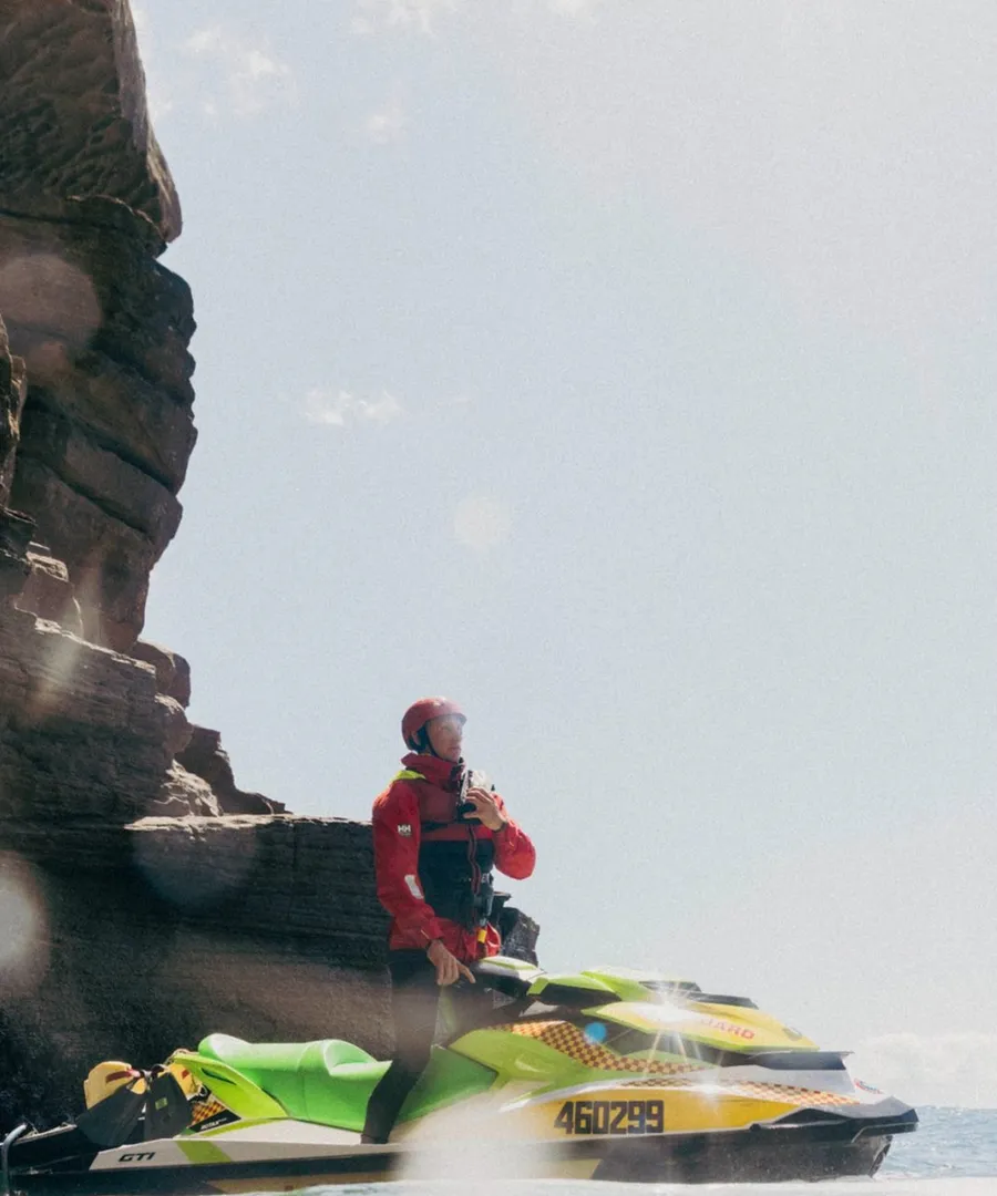 A rescue lifeguard on a jetski beneath the cliffs